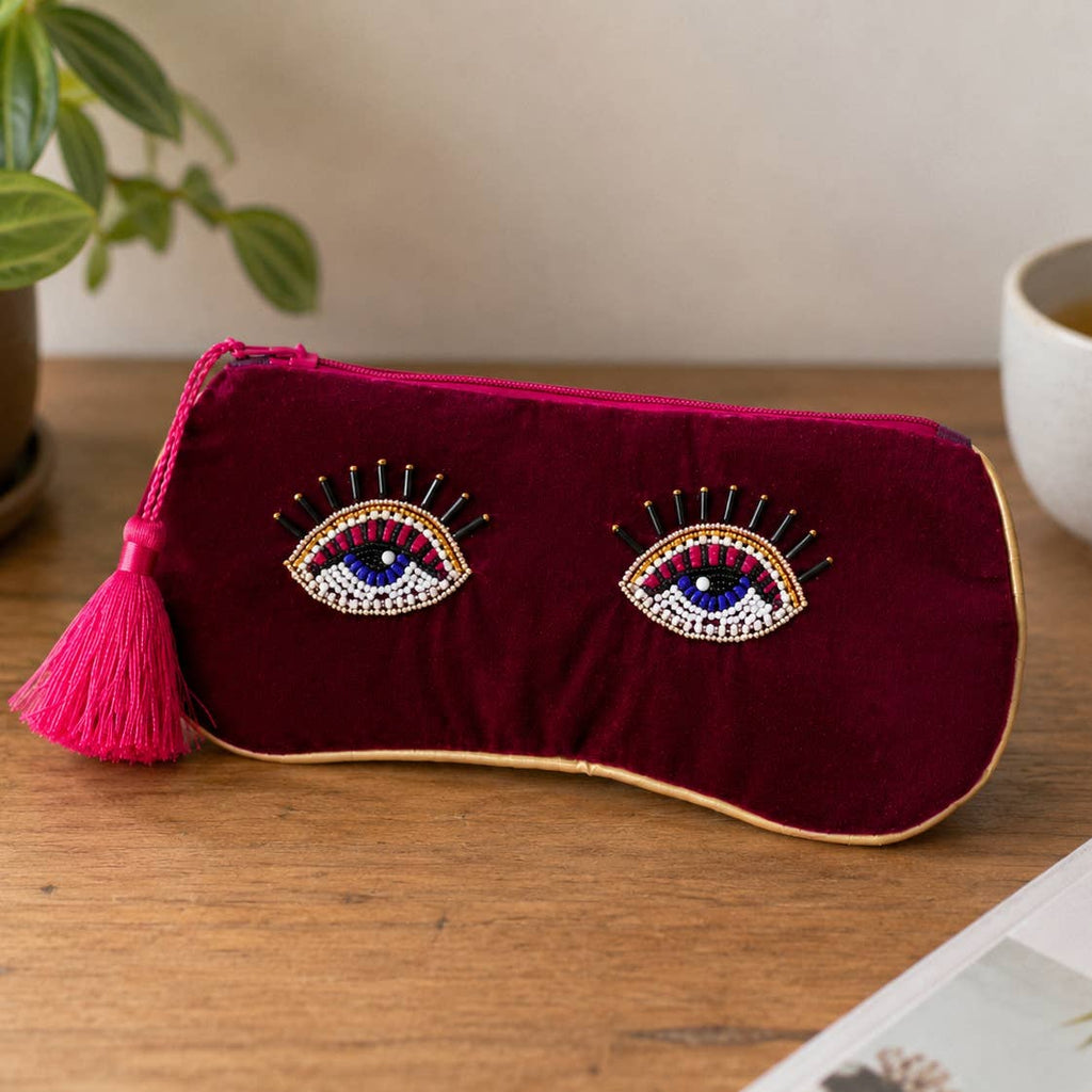 Burgundy velvet beaded eye glasses pouch with pink tassel displayed on a wooden table.