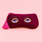 Burgundy velvet glasses pouch with two colourful beaded eye motifs, gold edging and a bright pink tassel.