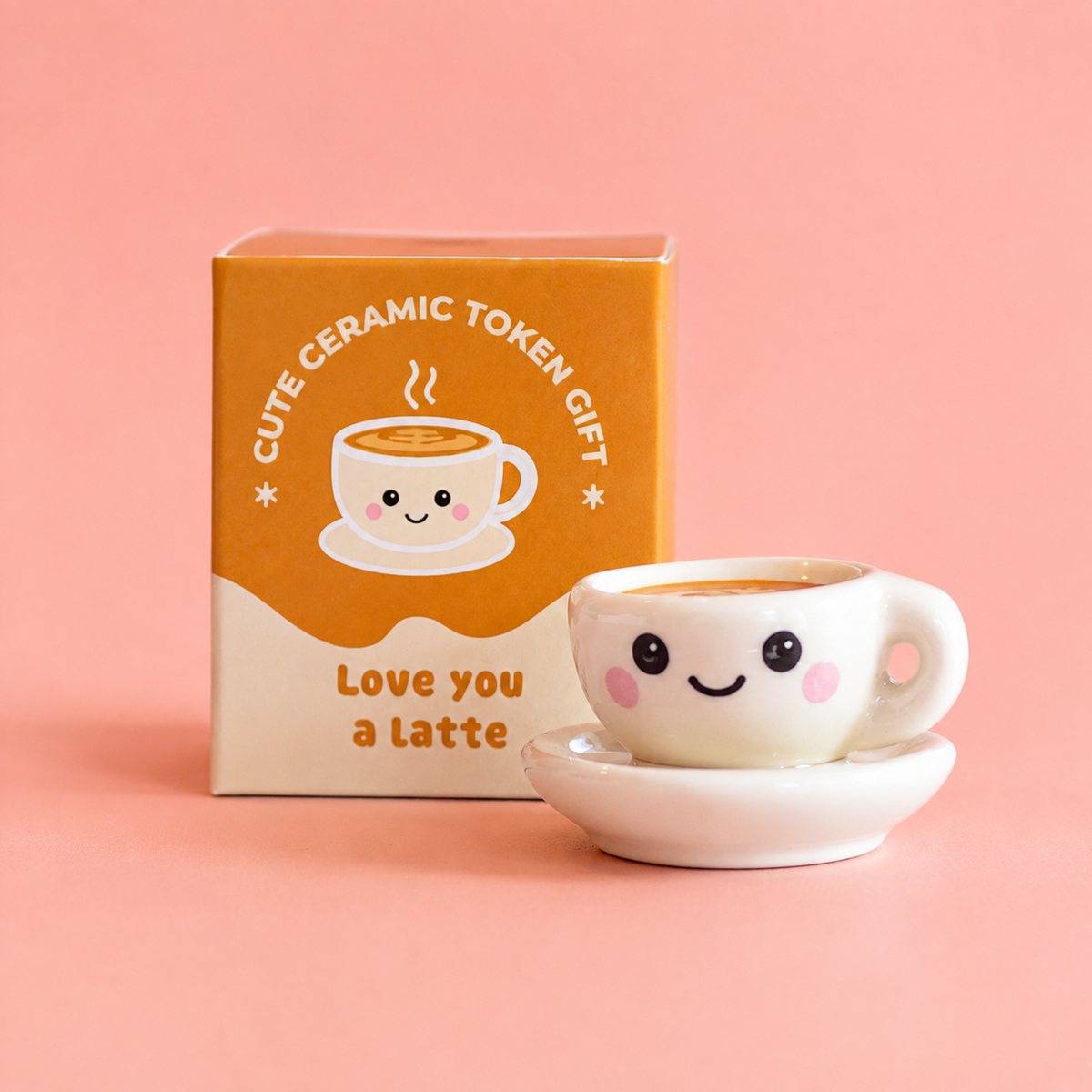 Love You A Latte ceramic coffee cup token with smiling face and gift box on a soft pink background.