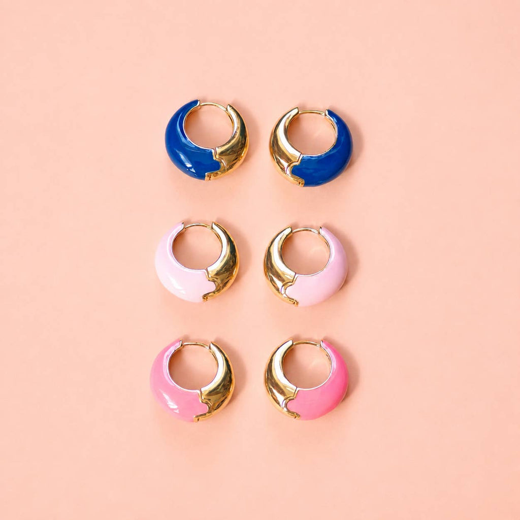 Three pairs of colourful enamel huggie hoop earrings in cobalt blue, pale pink and bright pink with gold-tone detailing.