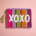 Colourful striped beaded zip pouch with bold white ‘XOXO’ lettering and metallic gold tassel zip pull.
