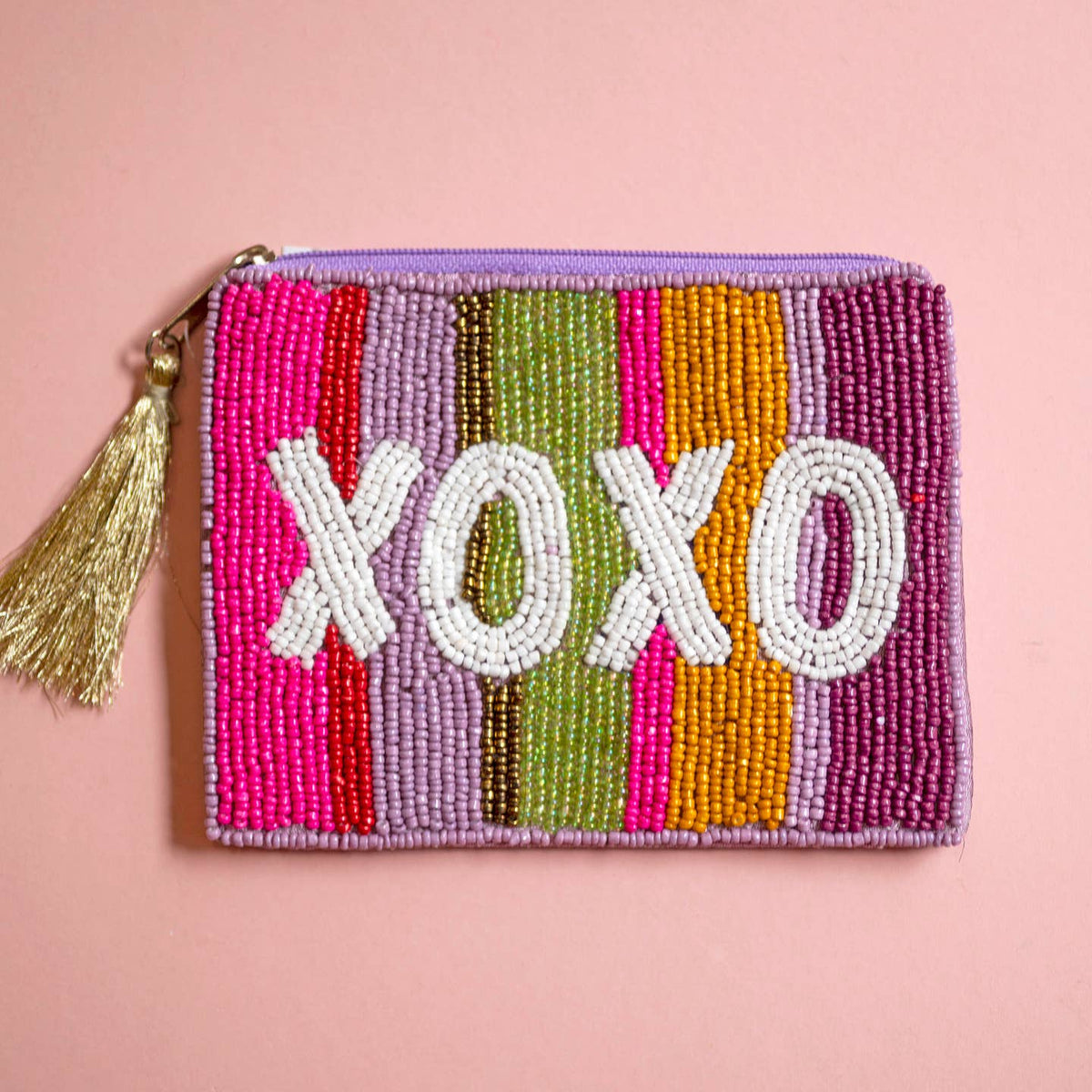 Colourful striped beaded zip pouch with bold white ‘XOXO’ lettering and metallic gold tassel zip pull.