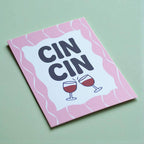 Colourful Cin Cin A5 art print featuring two clinking wine glasses, bold navy lettering and a playful pink wavy design.