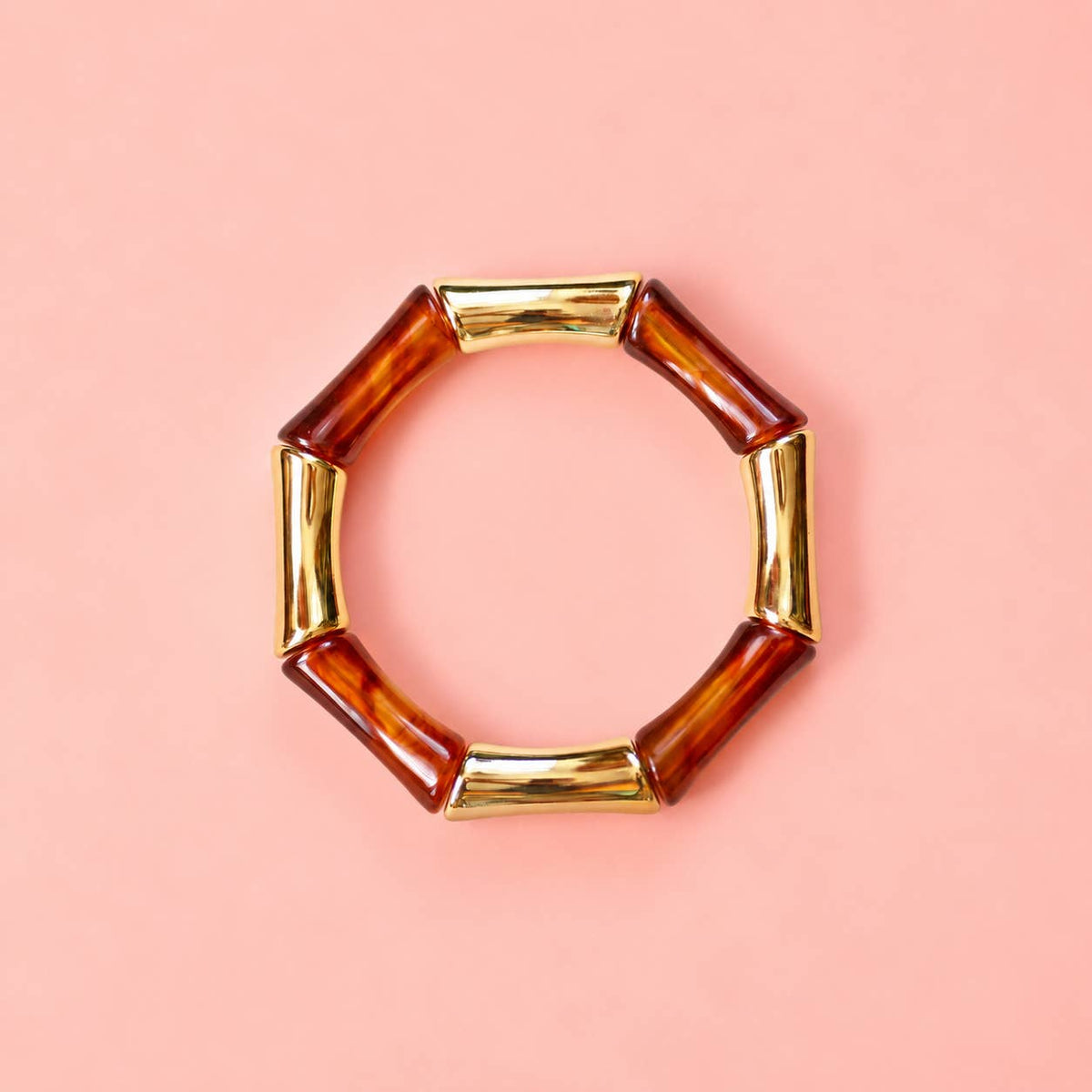 Tortoiseshell effect acrylic and gold bamboo inspired stretch bracelet on a pale pink background.