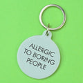 Silver round statement keyring with black Allergic to Boring People lettering and silver-tone metal keyring attachment.