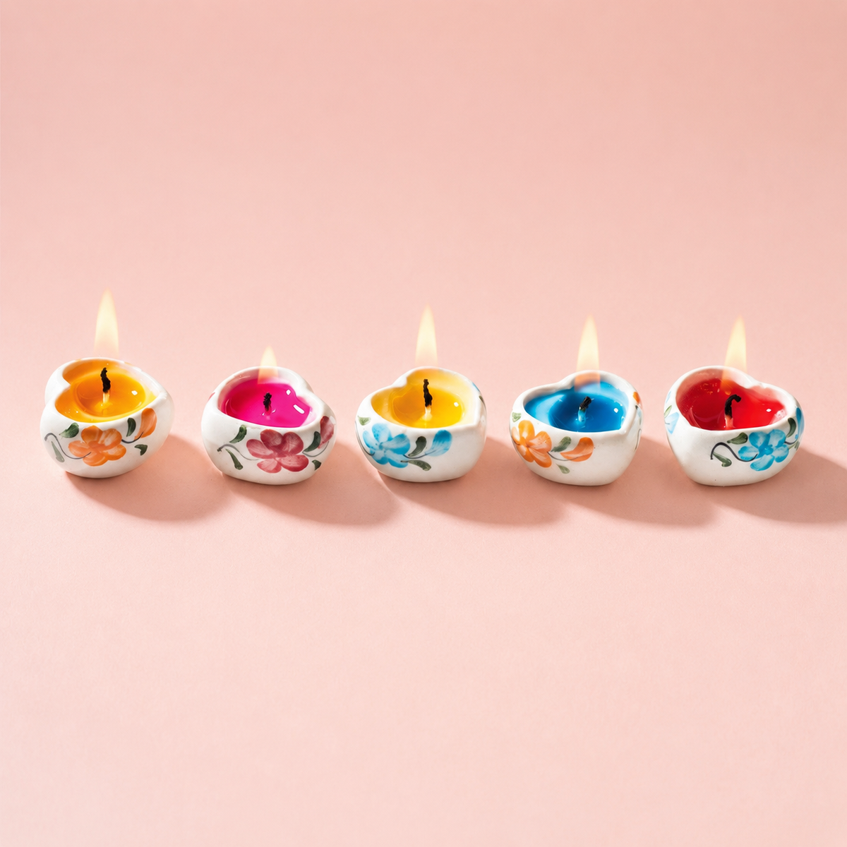 Tray of five colourful hand painted ceramic heart shaped mini candles in a wooden holder.