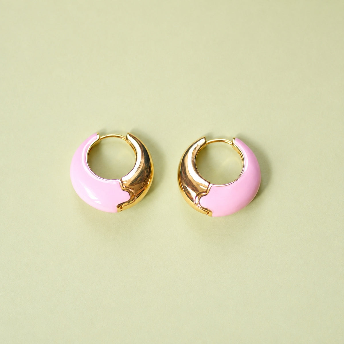 Pale pink enamel huggie hoop earrings with polished gold-tone detail.