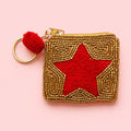 Mini keyring purse with a red star, gold beadwork, red pom pom and gold tone keyring on a pink background.
