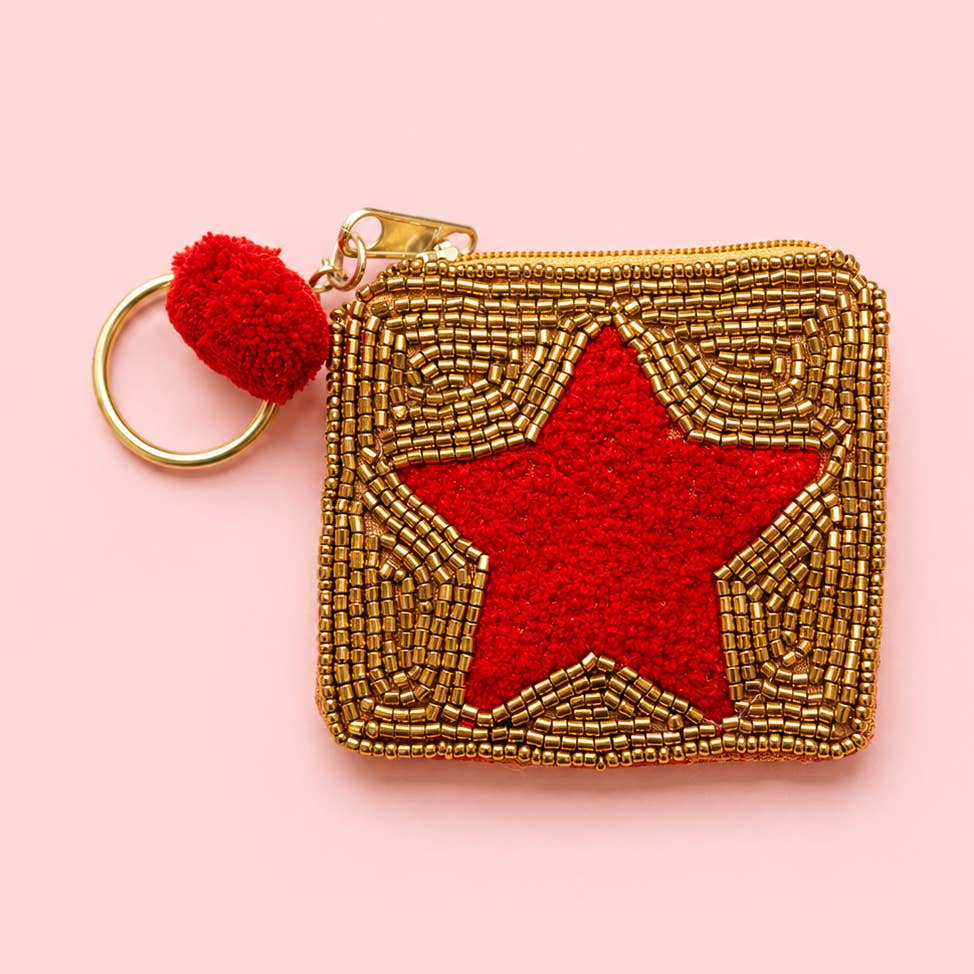 Mini keyring purse with a red star, gold beadwork, red pom pom and gold tone keyring on a pink background.