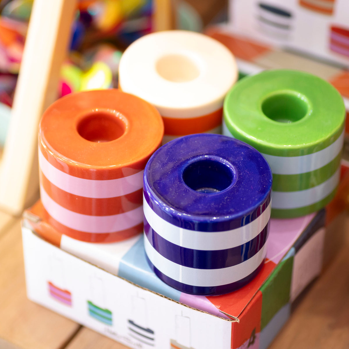Set of four chunky striped ceramic candlestick holders in purple, green, orange, red, pink and cream with colourful presentation box.