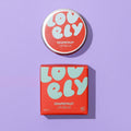 Grapefruit Lip Balm 10g tin and colourful orange and blue box on a lilac background.