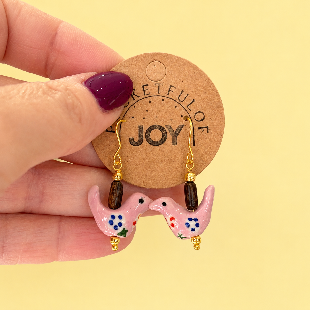 Limited edition pink bird drop earrings with colourful floral details, brown beads and gold tone hooks.