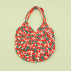 One of a kind handmade crochet bag in coral pink, blush and teal on a pale green background.