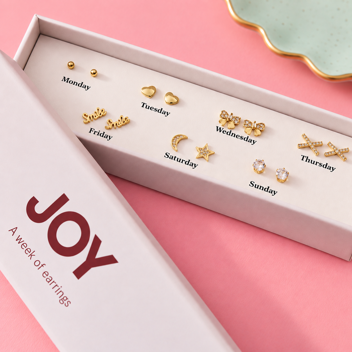 Gold plated Week of Earrings gift set with seven pairs of stud earrings displayed by day in an open white JOY box.