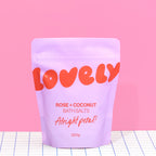 Rose and Coconut Bath Salts in lilac Alright Petal packaging against a bright pink background.