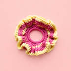 One of a kind Pink Lemonade crochet scrunchie handmade in bright pink and soft yellow on a pale pink background.