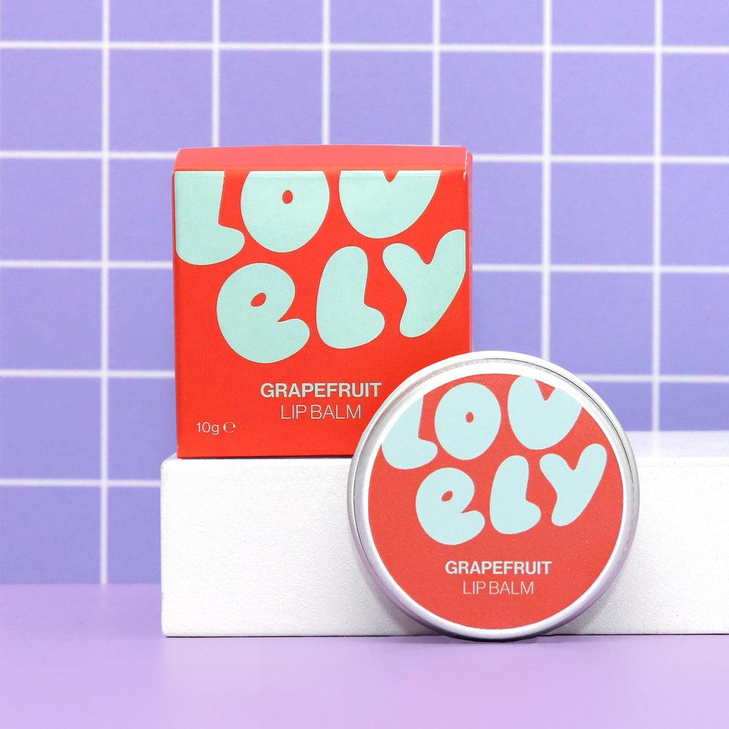 Grapefruit Lip Balm tin and colourful orange box displayed against a lilac tiled background.