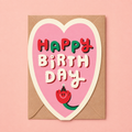 Pink heart shaped Happy Birthday greeting card with colourful retro lettering and a small smiling character wearing a party hat.

