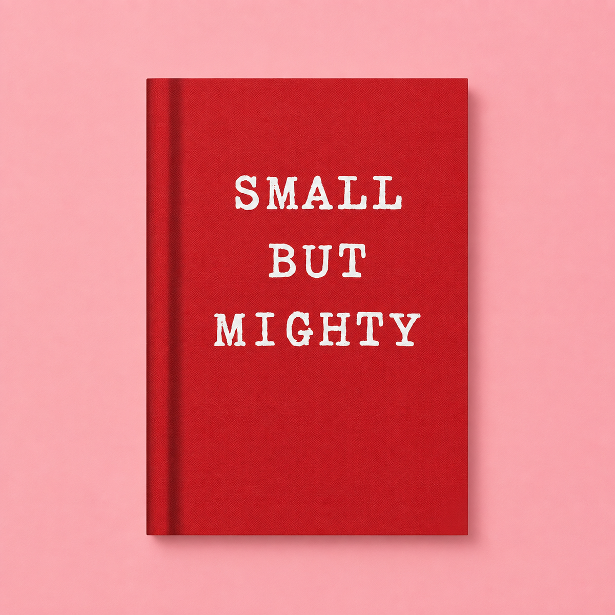 Bright red A7 fabric hardback notebook with white Small But Mighty lettering on a soft pink background.