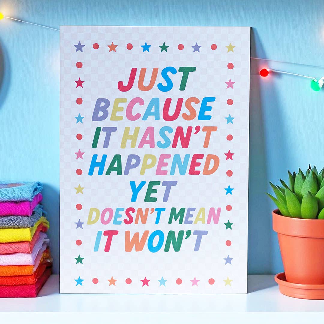 Uplifting A5 print with colourful motivational wording, playful stars and dots, displayed against a bright blue wall.