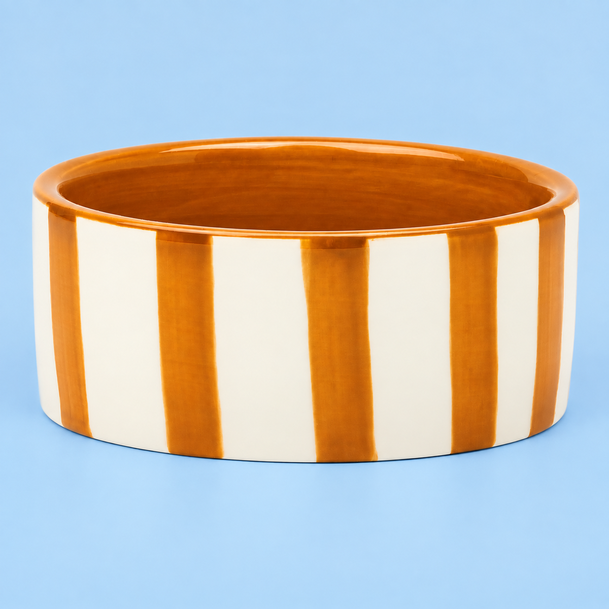 Hand painted mustard and cream striped ceramic wine bottle coaster on a blue background