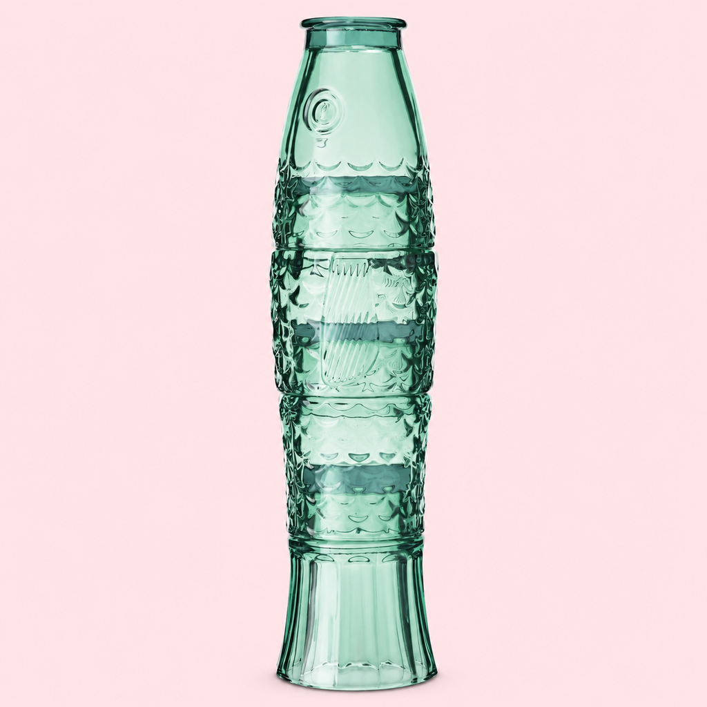 Four green glass tumblers stacked together to create a tall textured fish on a soft pink background.