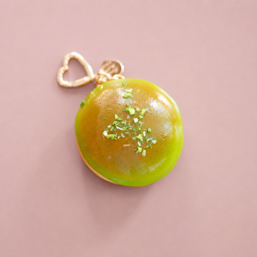 Top view of green apple glaze doughnut bag charm with realistic icing and gold heart shaped clip.