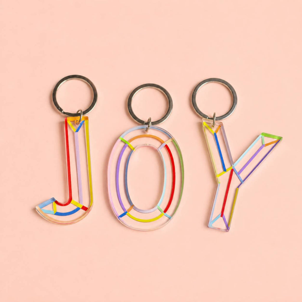 Colourful initial keychains spelling JOY with transparent acrylic letters, multicoloured details and silver-tone rings.