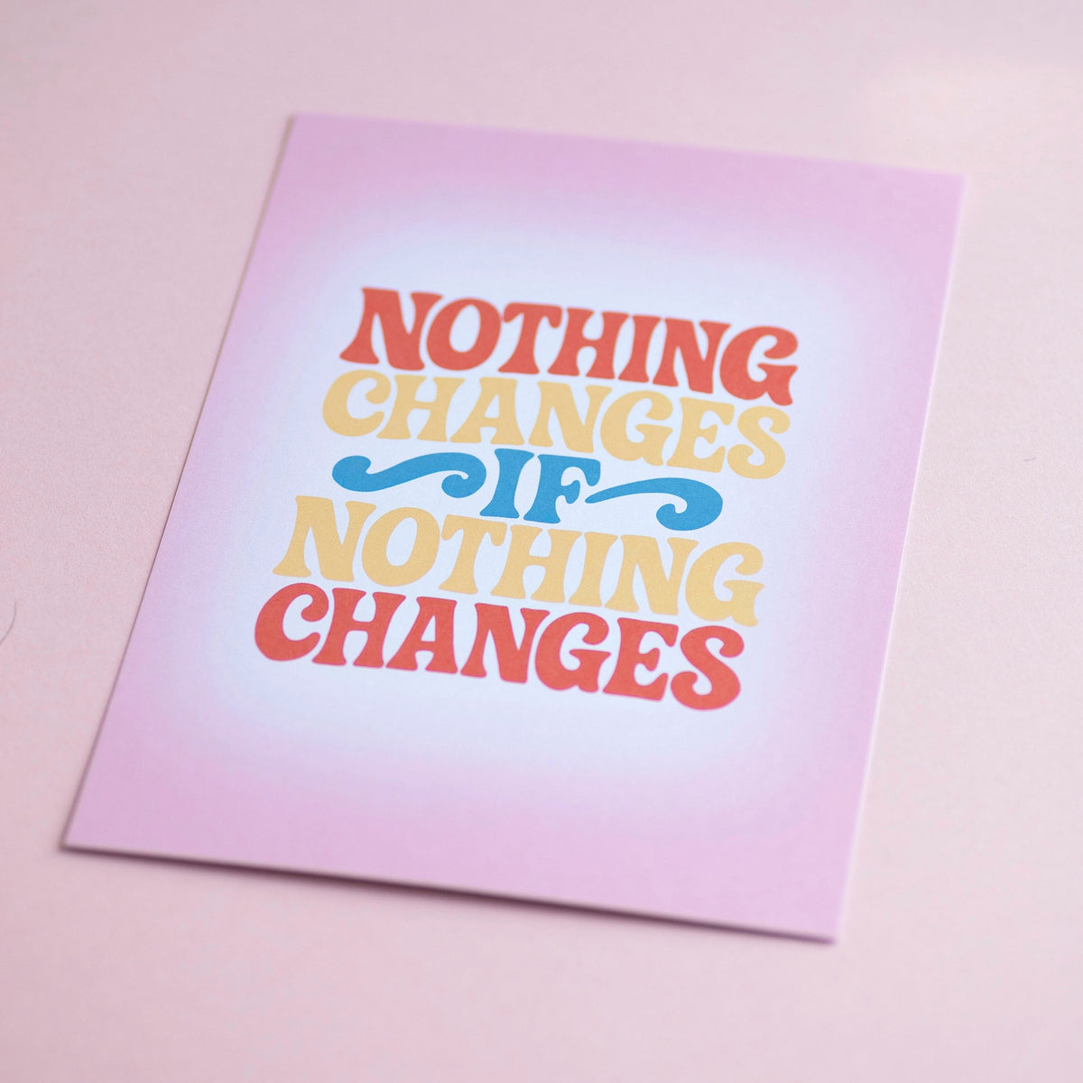 Joyful Nothing Changes If Nothing Changes A5 print with colourful retro lettering, photographed against a soft pink background.