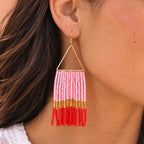 Pink, red and gold beaded fringe statement earring worn on the ear.