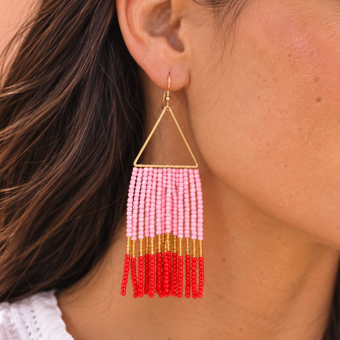 Pink, red and gold beaded fringe statement earring worn on the ear.
