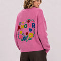 Back view of woman wearing pink jumper with large colourful floral AMOUR embroidery.