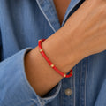 Red enamel bamboo style bangle with gold tone detailing worn on the wrist.