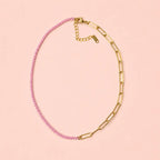 Two tone pale pink and gold plated stainless steel chain necklace on a soft peach pink background.