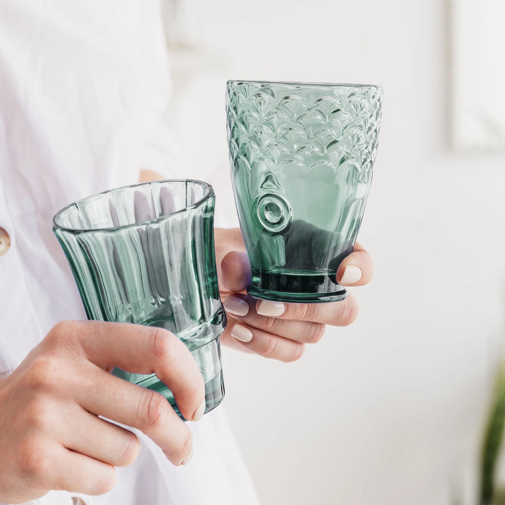 Two green fish stacking tumblers held in hands showing their different shapes and textured details.