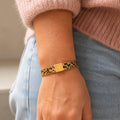 Leopard print magnetic bracelet worn on the wrist with a pink jumper and blue jeans.