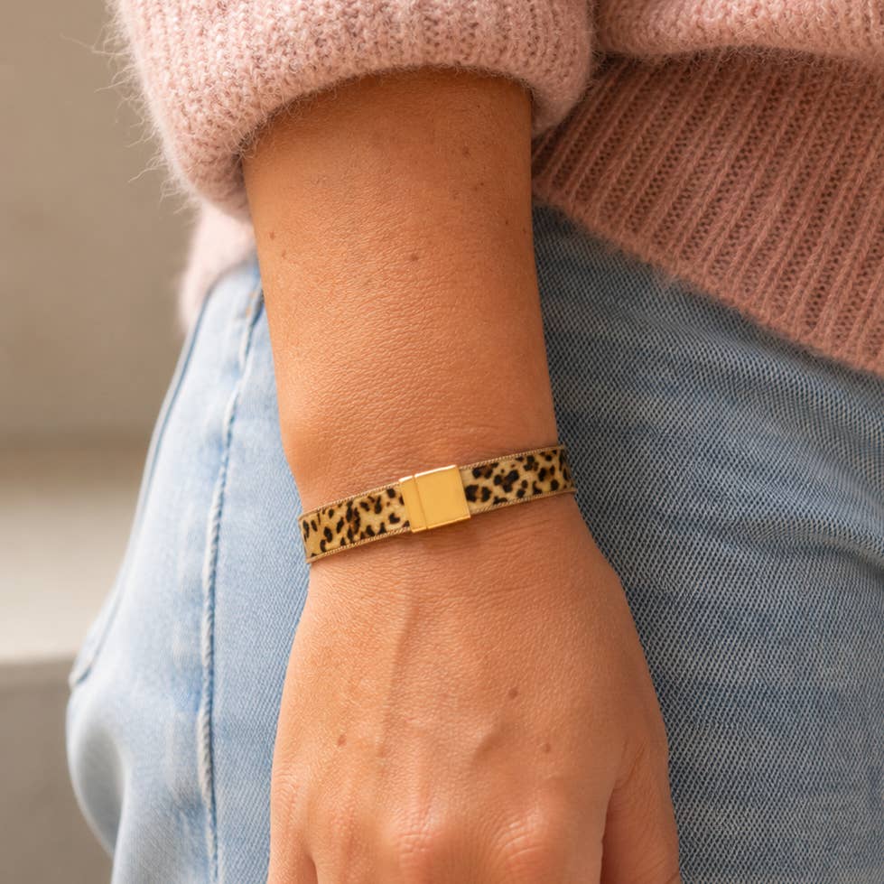 Leopard print magnetic bracelet worn on the wrist with a pink jumper and blue jeans.
