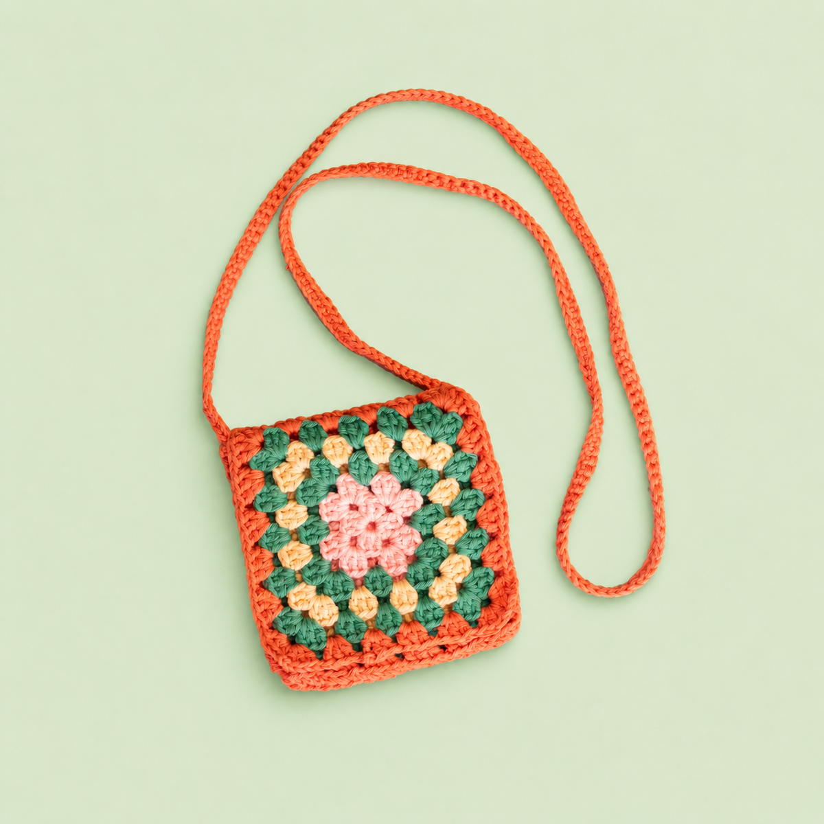 One of a kind mini crochet crossbody bag handmade by Corrine in orange, green, yellow and pink with a long strap and flap.
