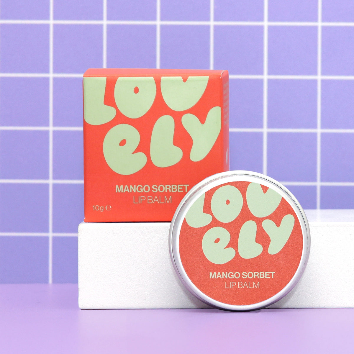 Mango Sorbet Lip Balm 10g tin and colourful orange box on a lilac background.
