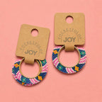 Pair of pink multi geometric beaded hoop earrings displayed on Pocketful of JOY jewellery cards.