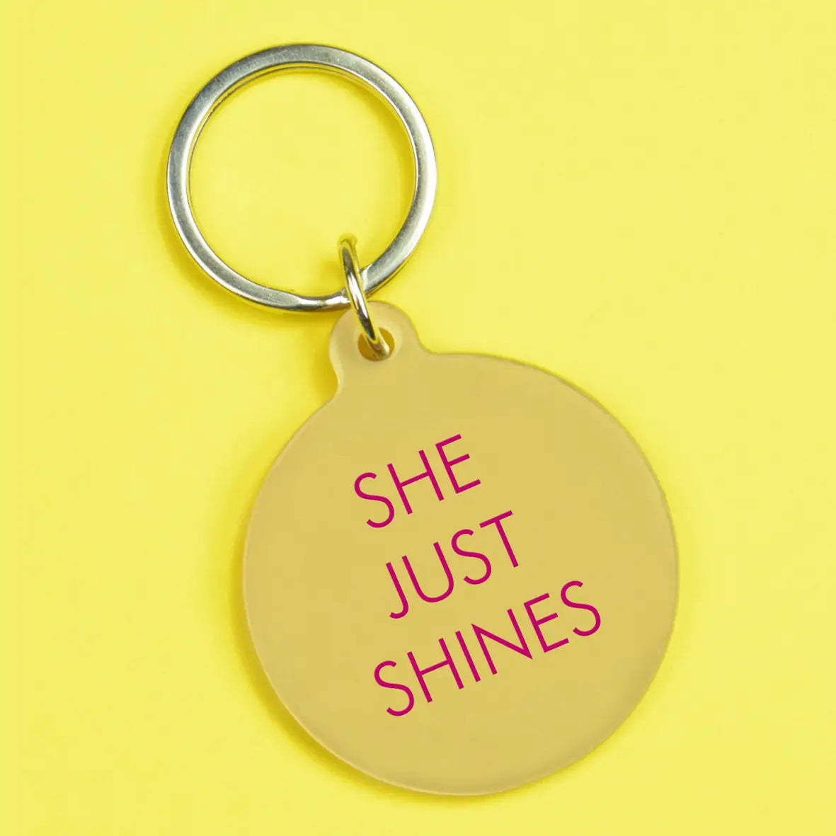 Sunshine yellow round keyring with hot pink She Just Shines lettering and silver-tone metal keyring attachment.