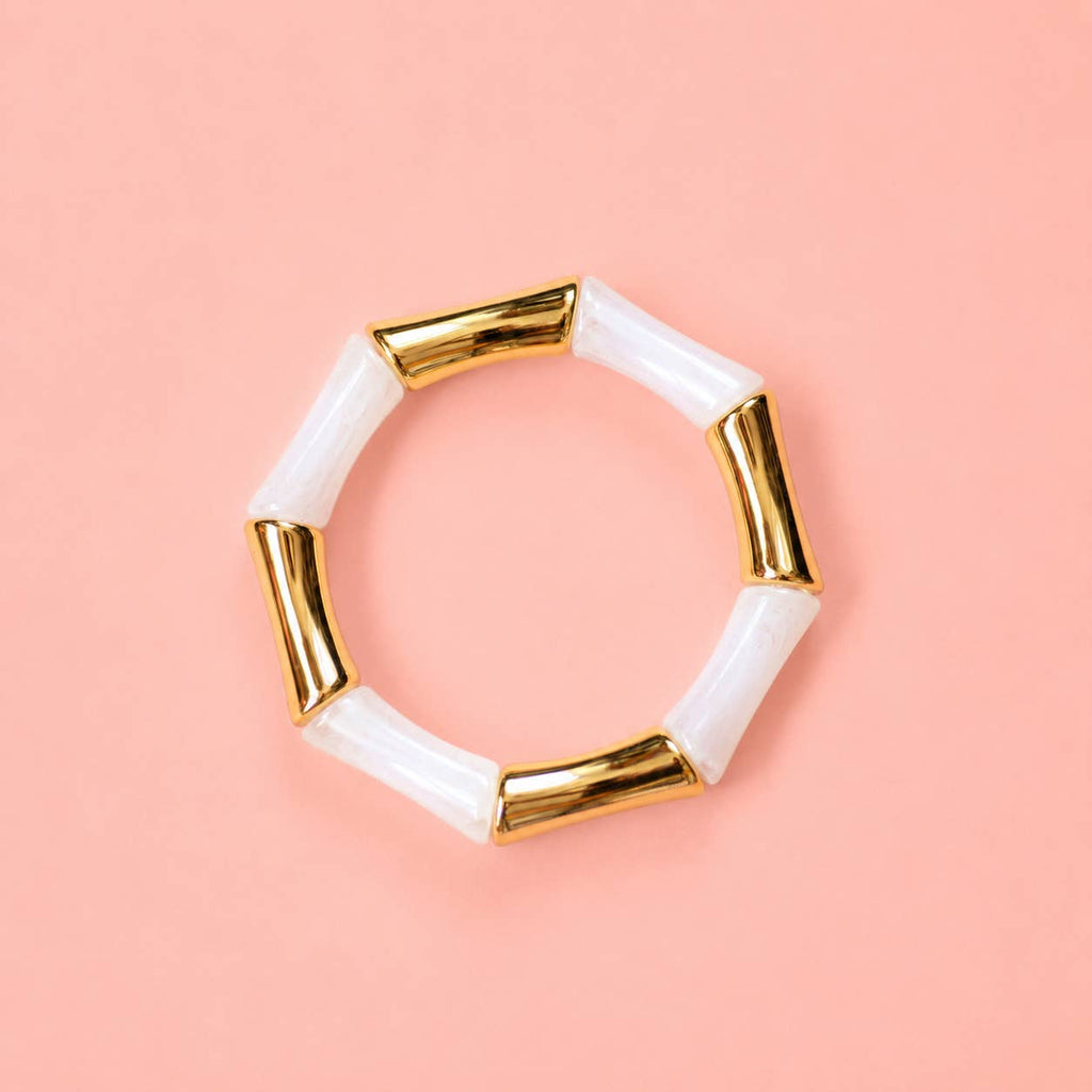Pearl white marbled acrylic and gold bamboo inspired stretch bracelet on a pale pink background.
