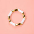 Pearl white marbled acrylic and gold bamboo inspired stretch bracelet on a pale pink background.