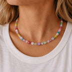Woman wearing a colourful pastel crystal cube bead necklace with a white top.