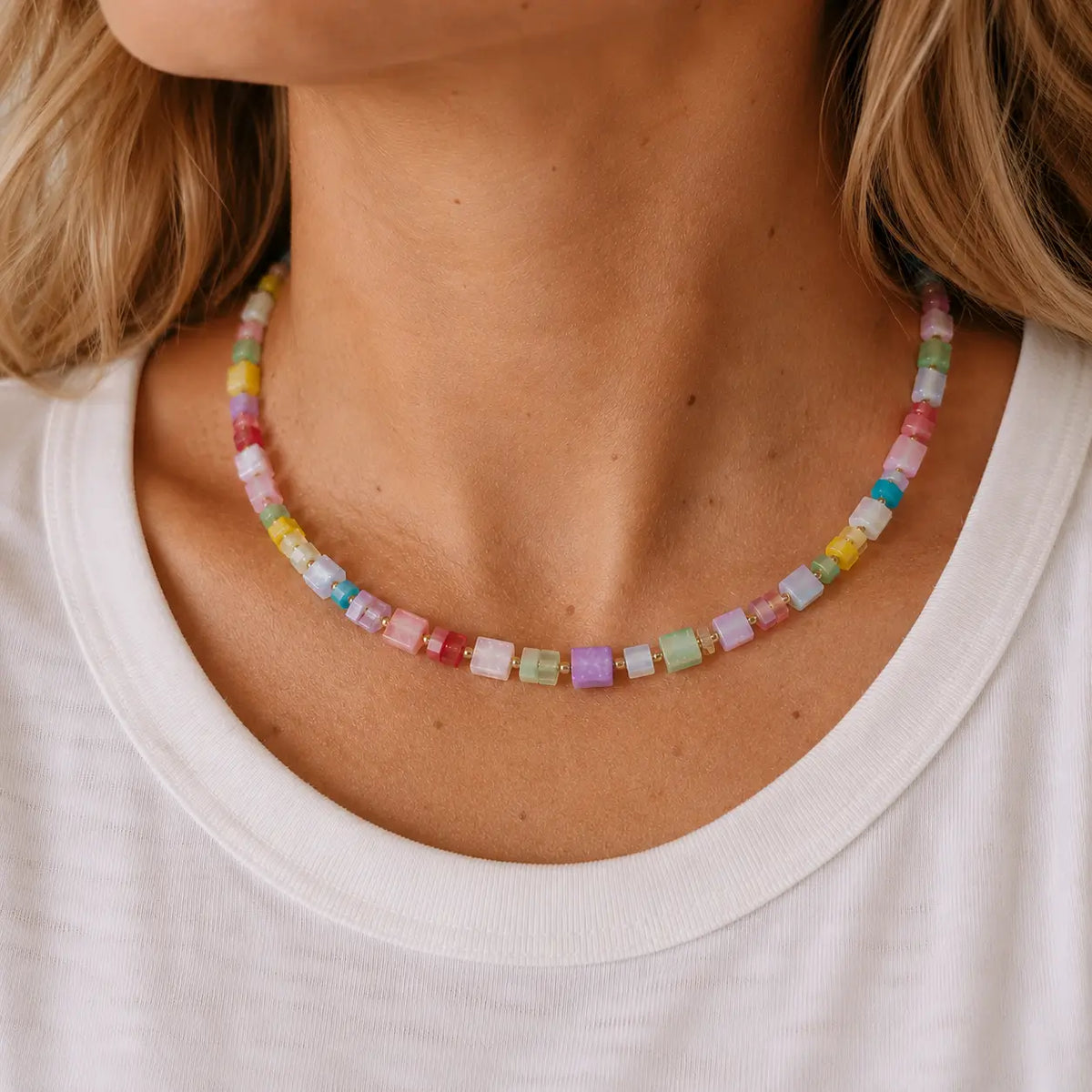 Woman wearing a colourful pastel crystal cube bead necklace with a white top.
