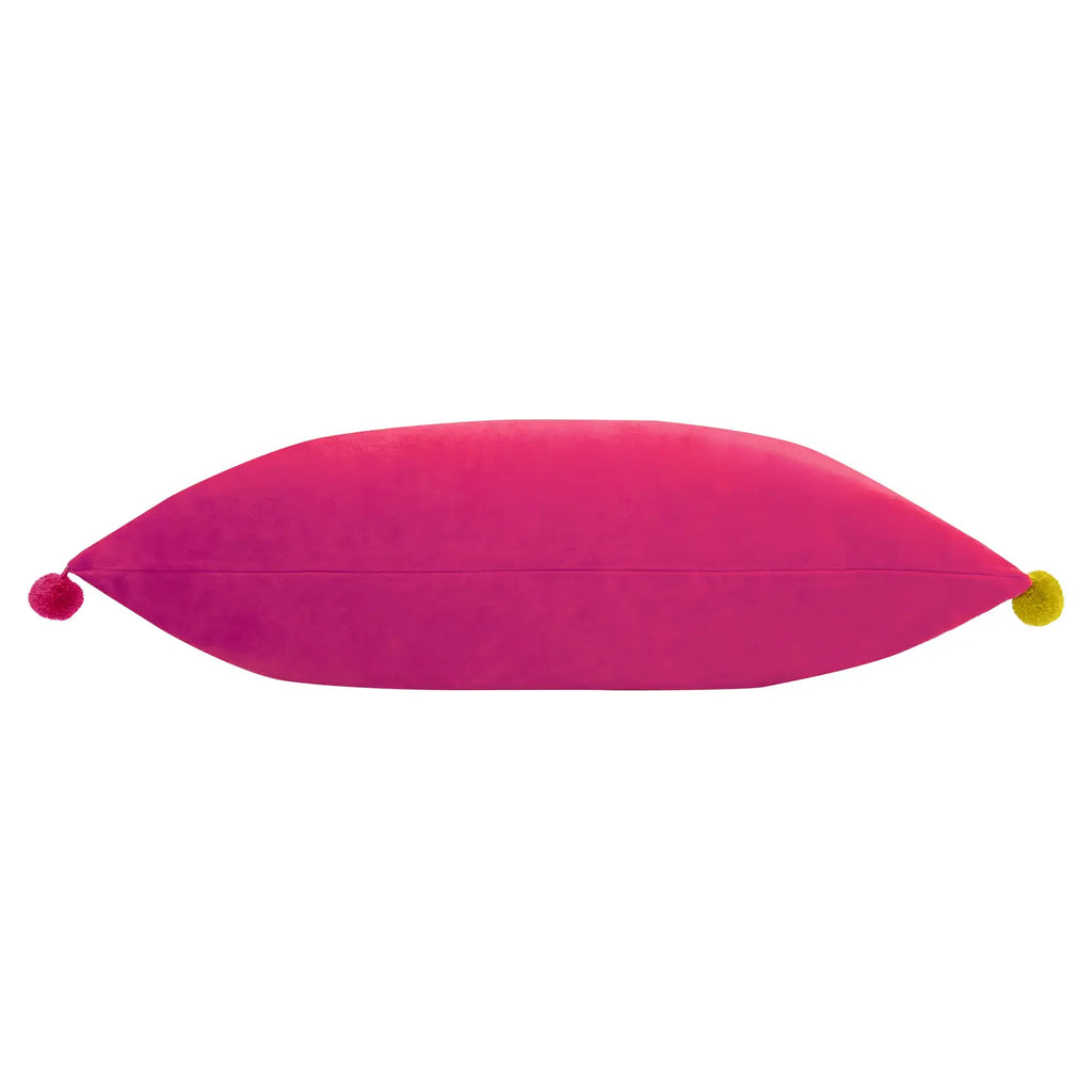 Side view of bright pink velvet Fiesta cushion showing the hidden zip and colourful pom pom details.