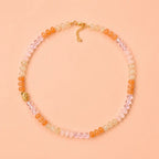 Sunrise natural stone bead necklace with peach, blush pink, honey and crystal accent beads on a peach background.