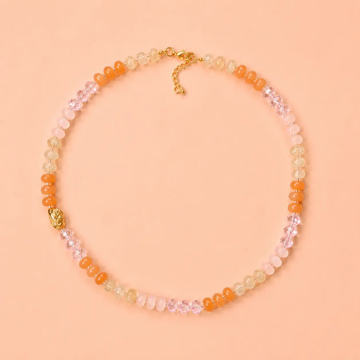 Sunrise natural stone bead necklace with peach, blush pink, honey and crystal accent beads on a peach background.