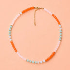 Coral Reef natural stone bead necklace with coral orange, blush pink, aqua and opalite style beads on a peach background.