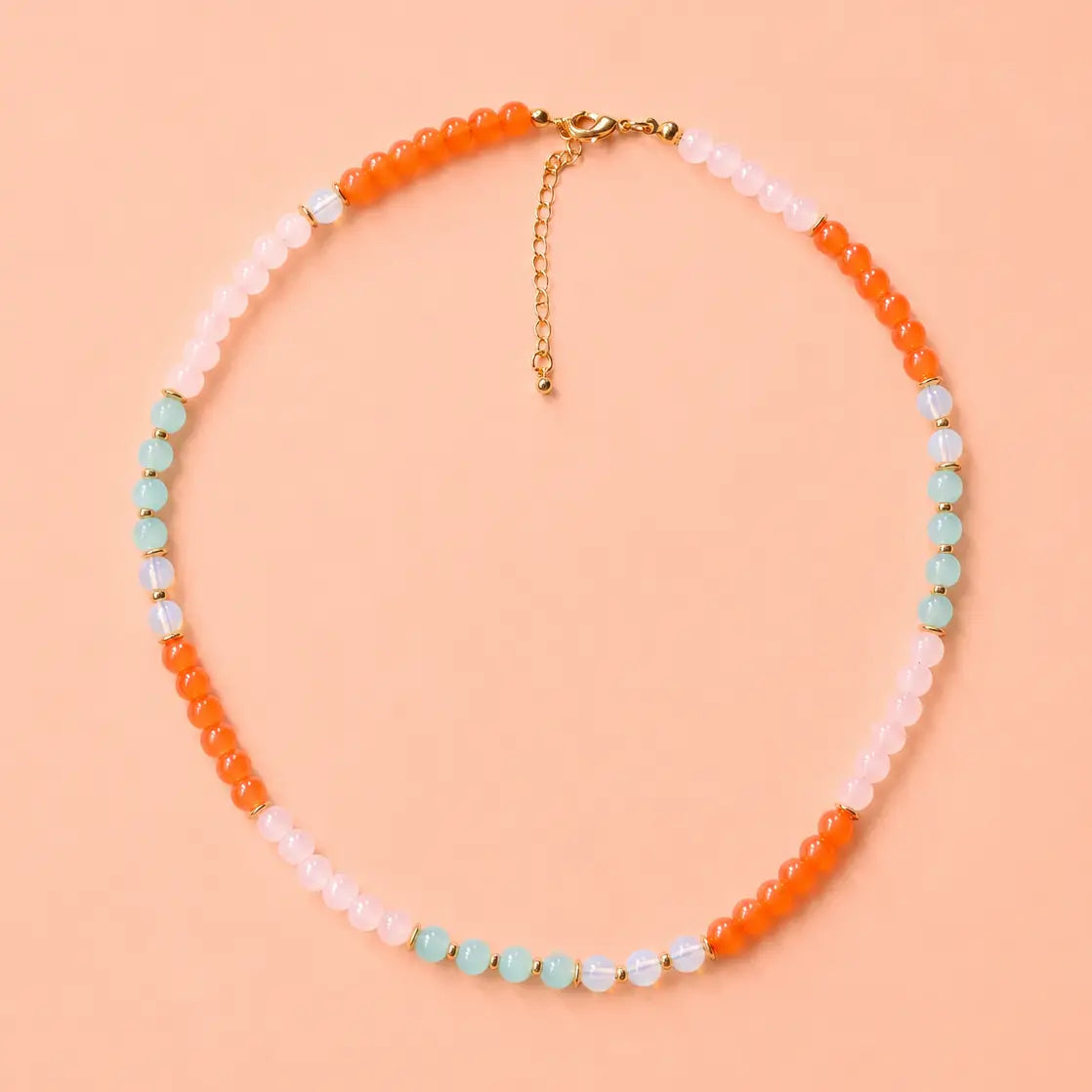 Coral Reef natural stone bead necklace with coral orange, blush pink, aqua and opalite style beads on a peach background.